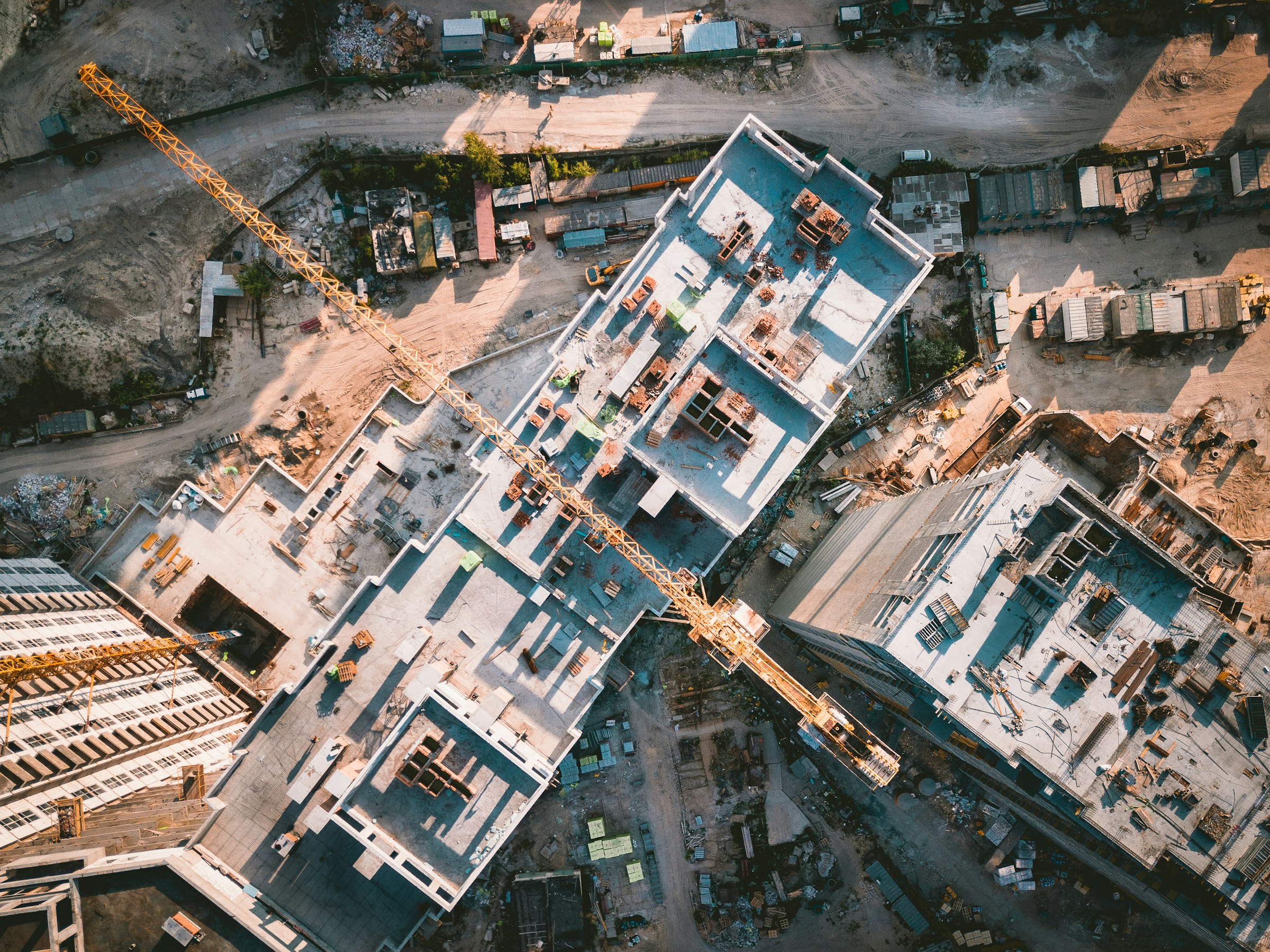 Straight-down aerial of an active construction site with a tower crane